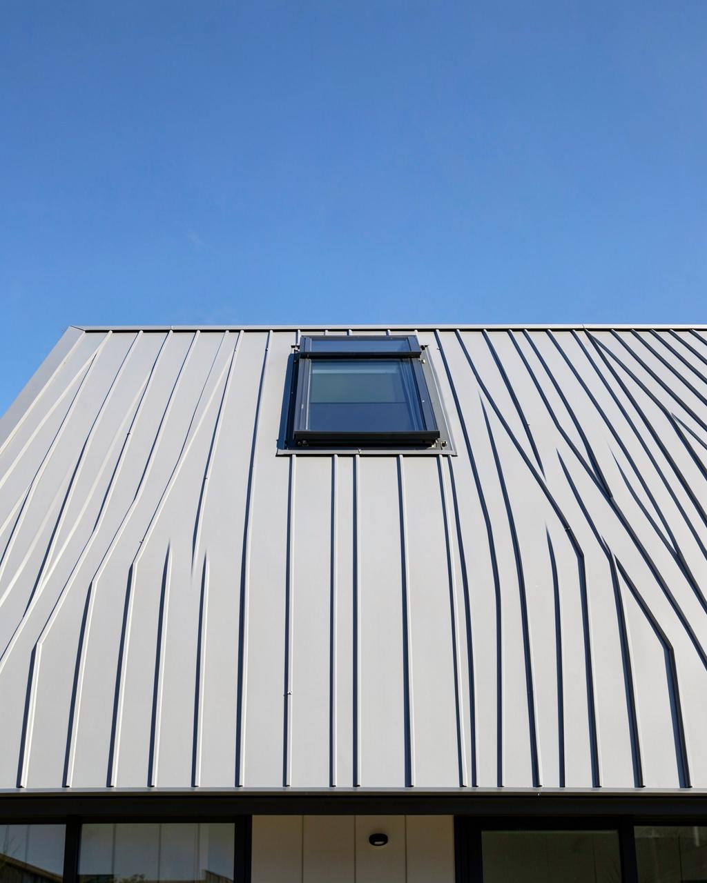Standing seam metal roof with a skylight against a blue sky